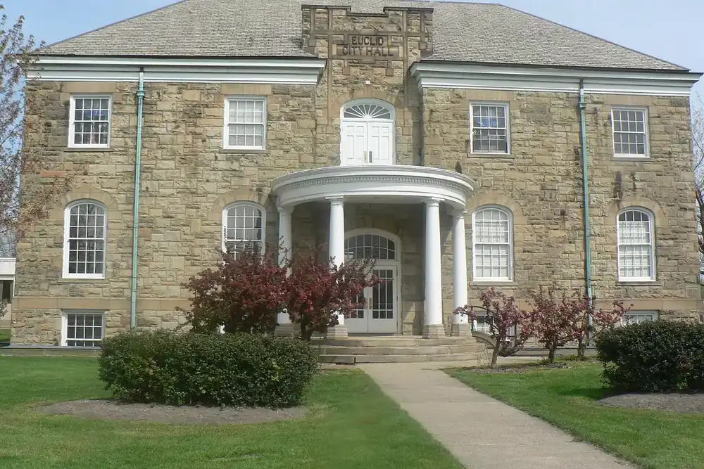 The stone Old City Hall with a columned porch on a quiet lawn in Euclid, Ohio