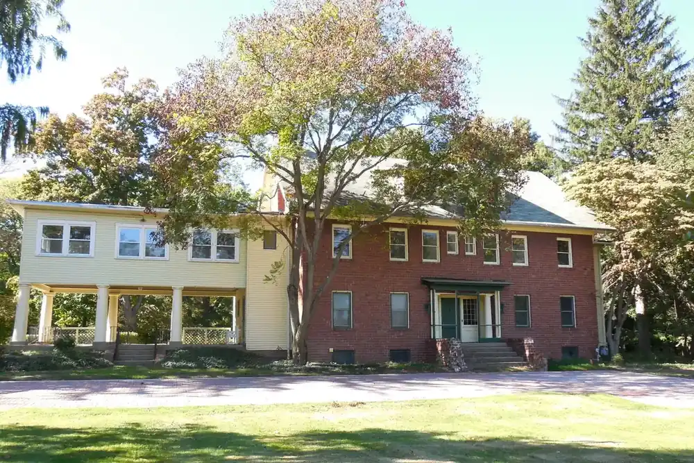 The brick and cream main house at Greenwood Farm under autumn trees in Richmond Heights, Ohio